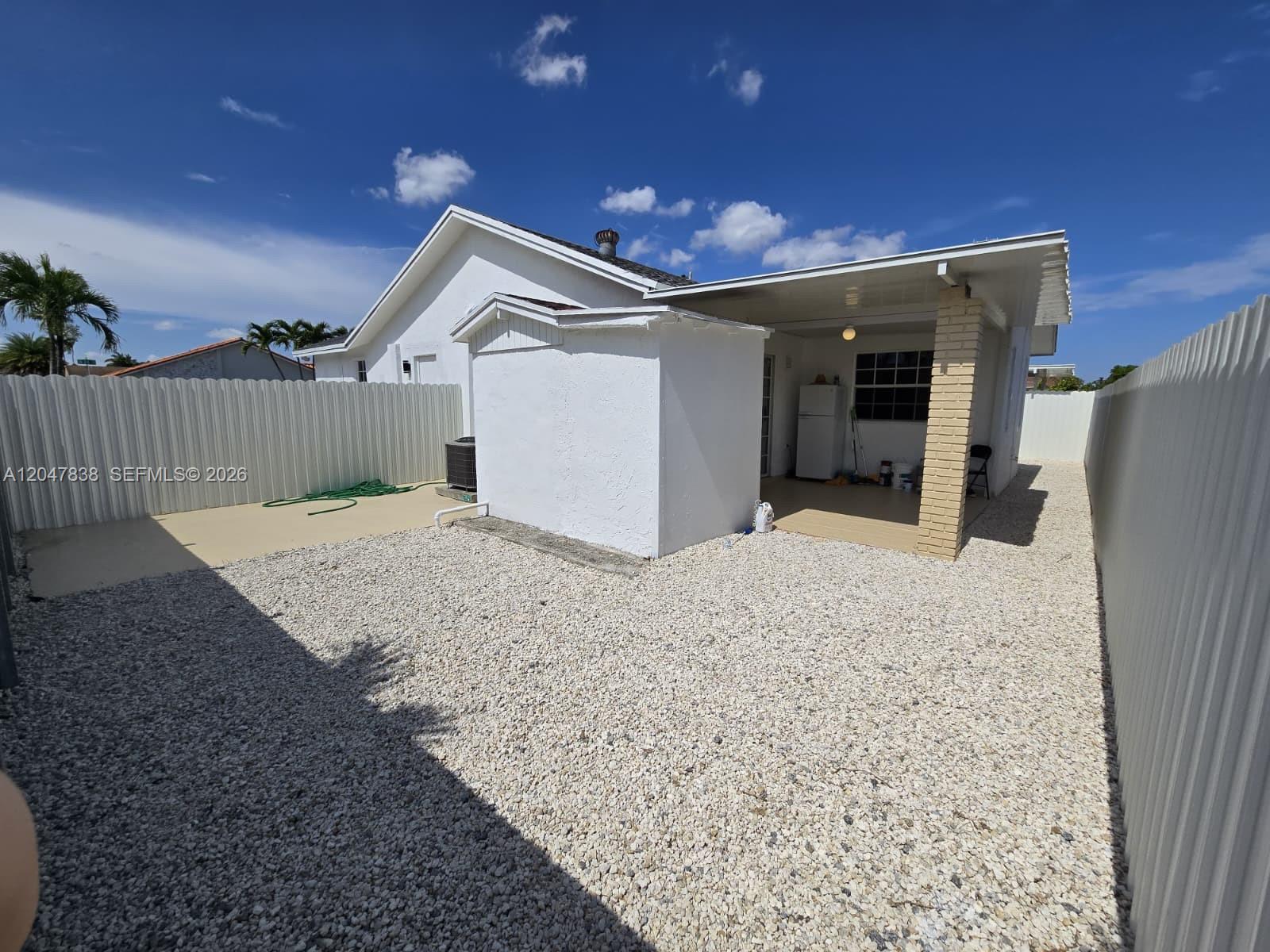 The backyard features a gravel ground, a white storage shed, and a covered patio area — 13470 SW 24th St, Miami FL 33175, MIAMI, FL