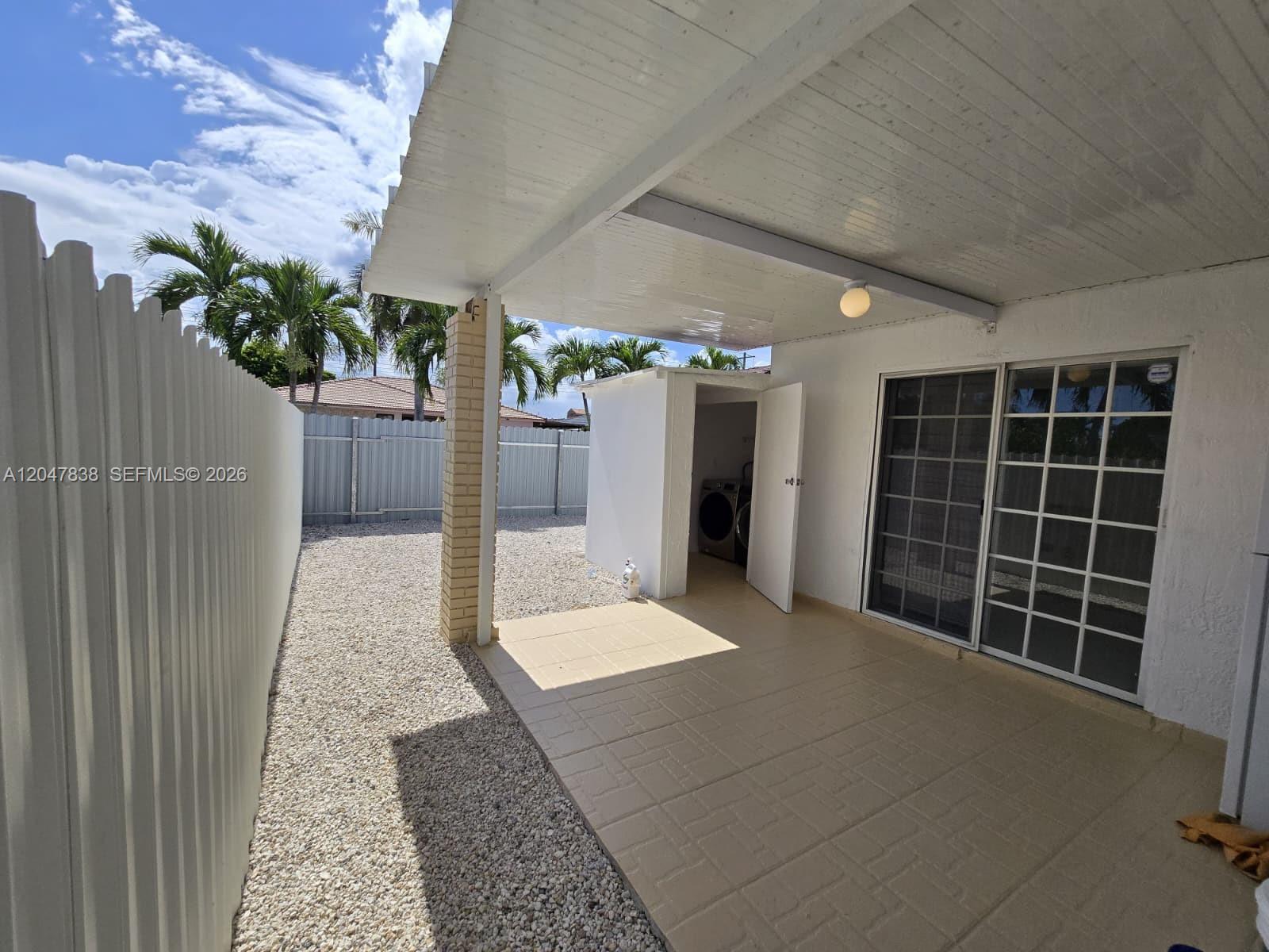 A covered patio with a tiled floor, gravel yard, and a small outdoor utility closet — 13470 SW 24th St, Miami FL 33175, MIAMI, FL