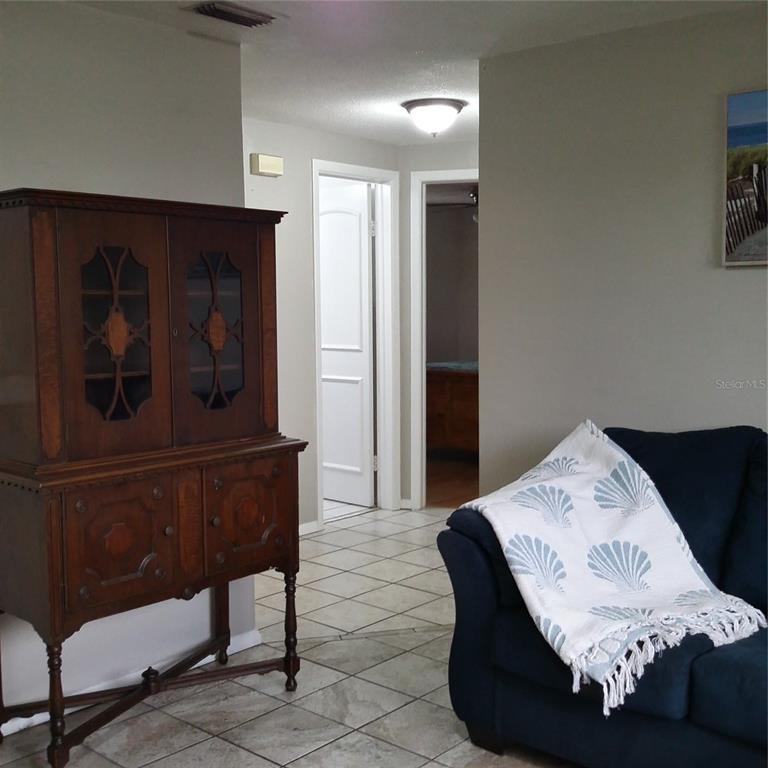 A dark wood hutch stands near a blue sofa in a room with tiled floors — 7725 ROTTINGHAM ROAD, PORT RICHEY, FL