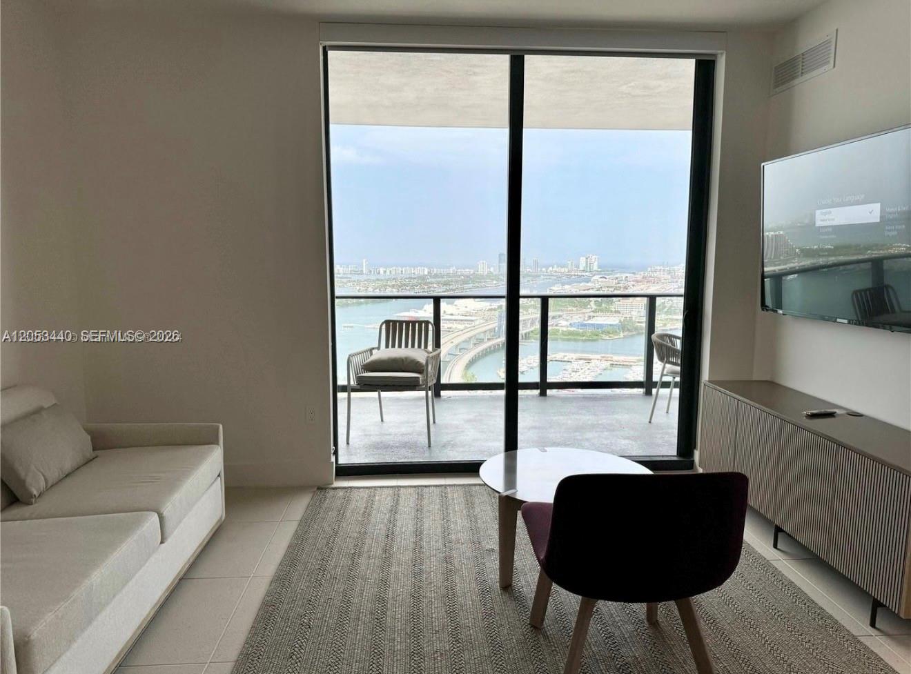 A living room features a sofa, a round coffee table, and a balcony with water views — 159 NE 6th St # 3215, Miami FL 33132, MIAMI, FL