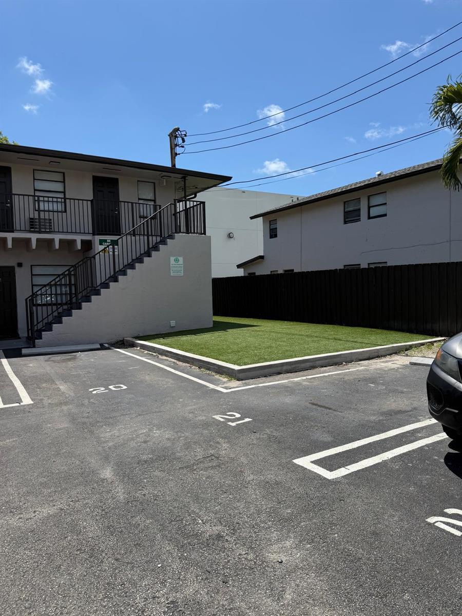 An exterior view of a two-story apartment building with a small lawn and parking spaces — 110 NW 7th Avenue # 18, Pompano Beach FL 33060, POMPANO BEACH, FL