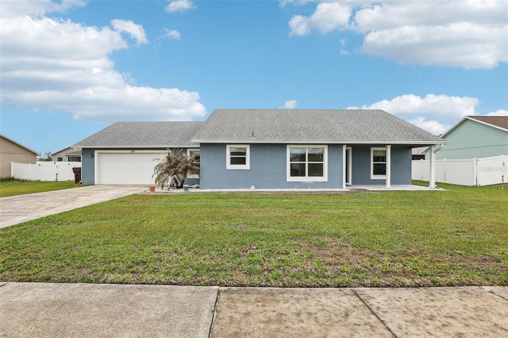 A single-story blue house with a two-car garage and a front lawn — 264 CHICAGO AVENUE W, HAINES CITY, FL