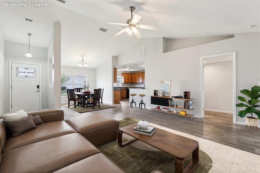 A living room with a brown sectional, coffee table, and open access to a dining area — 264 CHICAGO AVENUE W, HAINES CITY, FL