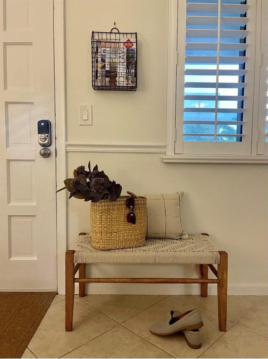 A wooden bench with a woven seat sits in an entryway next to a door — 1202 Palm Trail # 6, Delray Beach FL 33483, DELRAY BEACH, FL