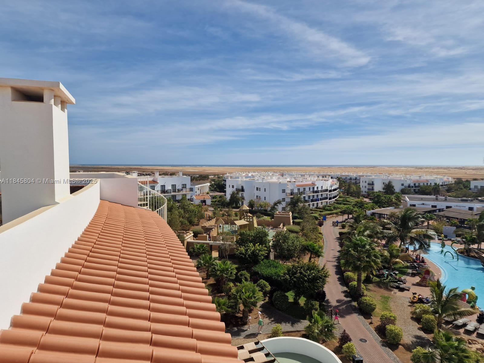 An elevated view shows a tiled roof, resort buildings, palm trees, and a swimming pool — 4110 Rua Andrade Corvo # 6087, FL, FL