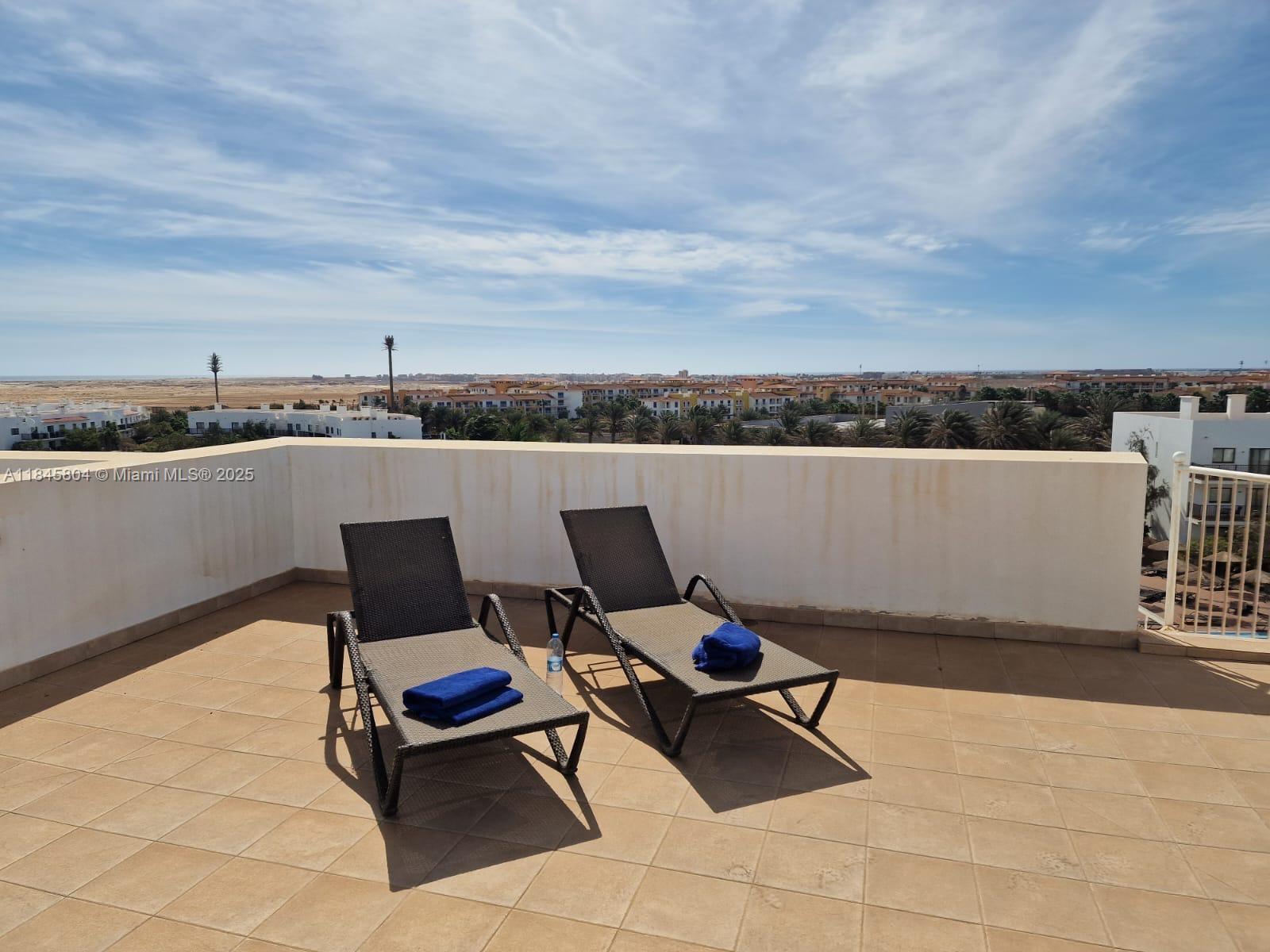 Two lounge chairs with blue towels sit on a tiled rooftop terrace overlooking a landscape — 4110 Rua Andrade Corvo # 6087, FL, FL