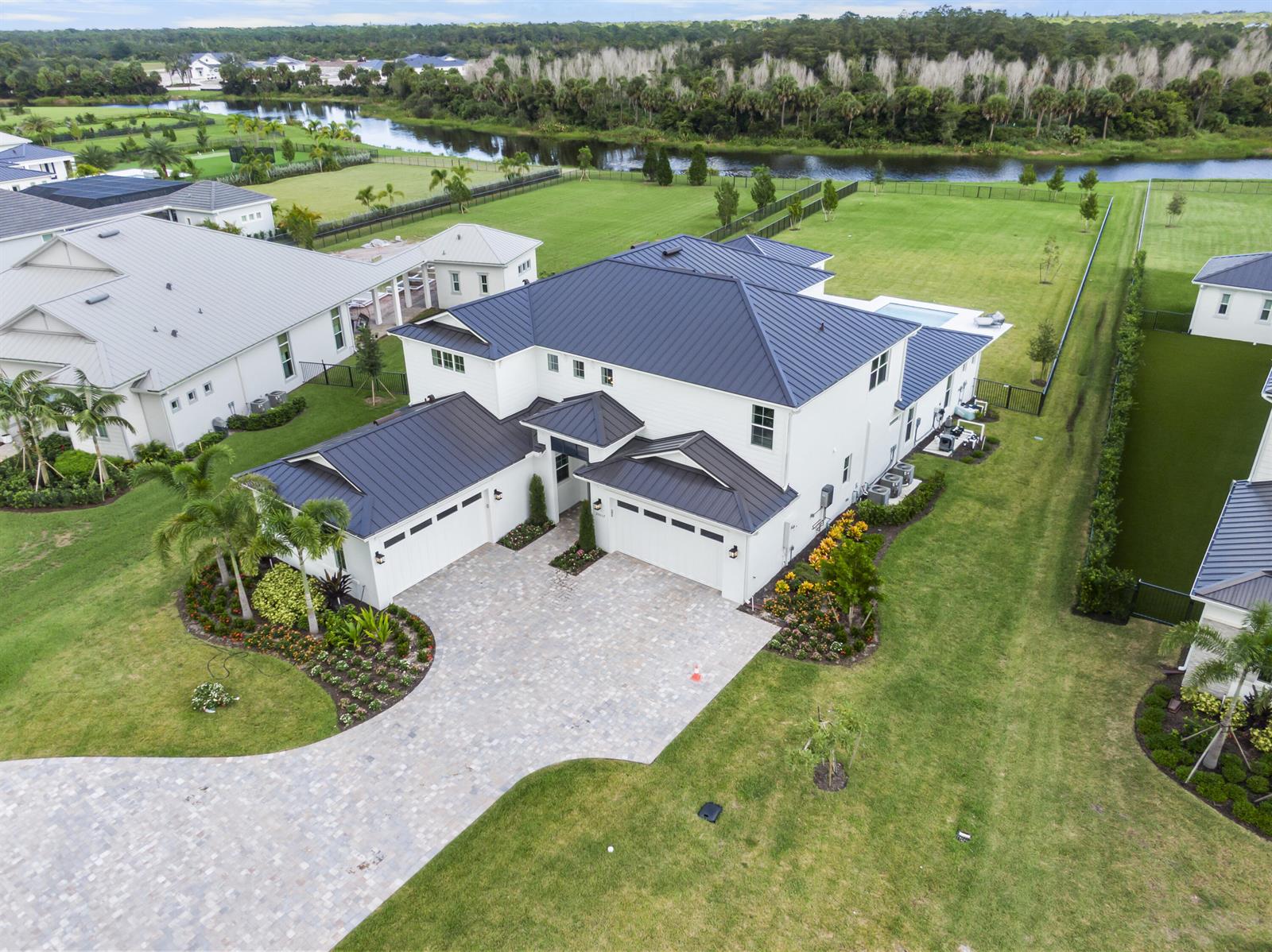 An aerial view shows a white two-story house with a dark metal roof and driveway — 20037 SE Bridgewater Drive, Jupiter FL 33458, JUPITER, FL