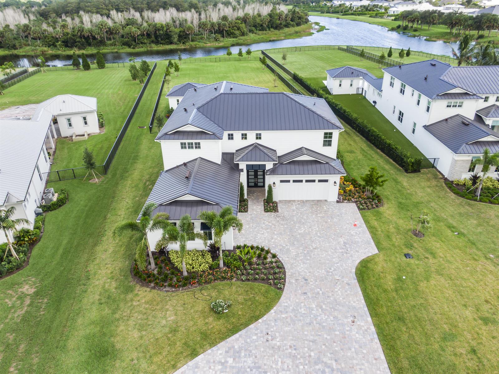 An aerial view shows a large white house with a dark metal roof and driveway — 20037 SE Bridgewater Drive, Jupiter FL 33458, JUPITER, FL