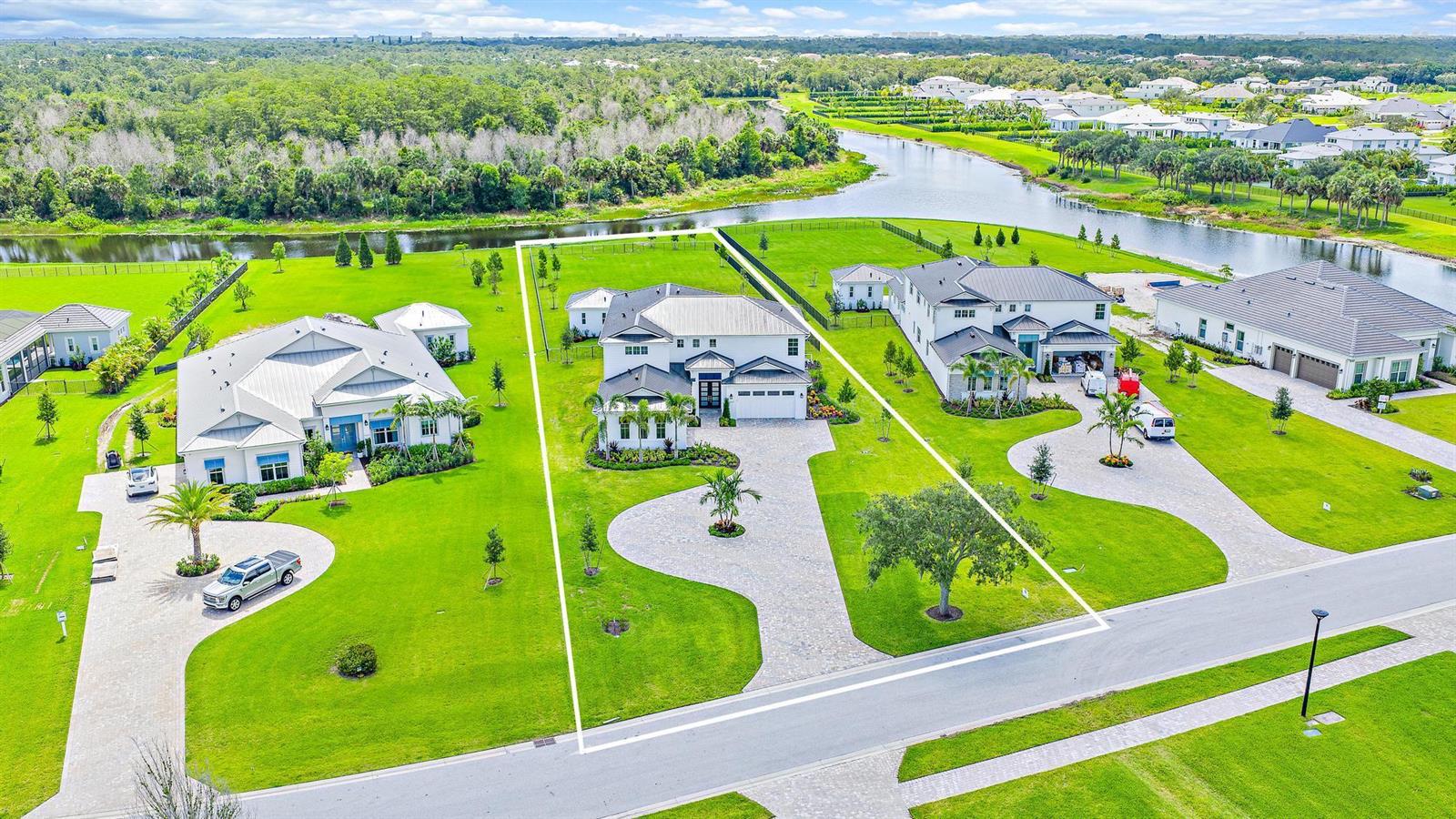 An aerial view shows three modern houses with large green lawns along a canal — 20037 SE Bridgewater Drive, Jupiter FL 33458, JUPITER, FL