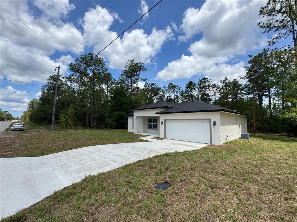 A single-story house with a white stucco exterior, a two-car garage, and a concrete driveway — 2523 W ANDROMEDAE DRIVE, CITRUS SPRINGS, FL