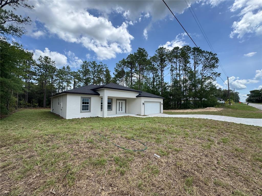 A newly constructed single-story house with white stucco walls and a dark roof — 2523 W ANDROMEDAE DRIVE, CITRUS SPRINGS, FL