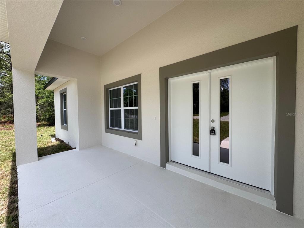 A covered porch features a white double front door and a window with gray trim — 2523 W ANDROMEDAE DRIVE, CITRUS SPRINGS, FL