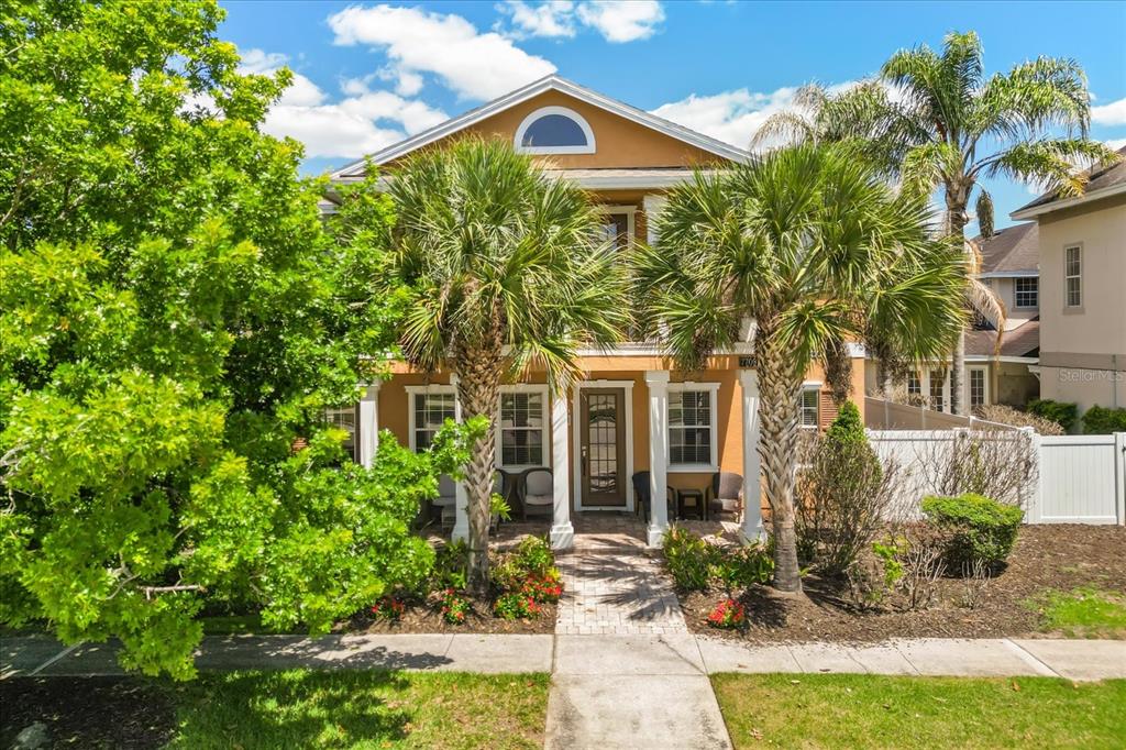 A two-story house with a tan exterior, white columns, and palm trees in the front yard — 7708 EXCITEMENT DRIVE, REUNION, FL