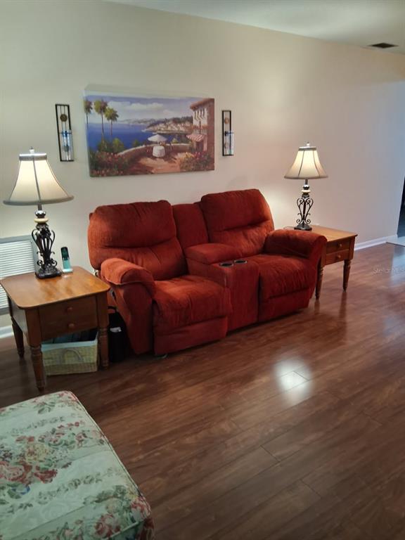 A living room features a red reclining loveseat between two wooden end tables with lamps — 6770 RIVIERA N, PINELLAS PARK, FL