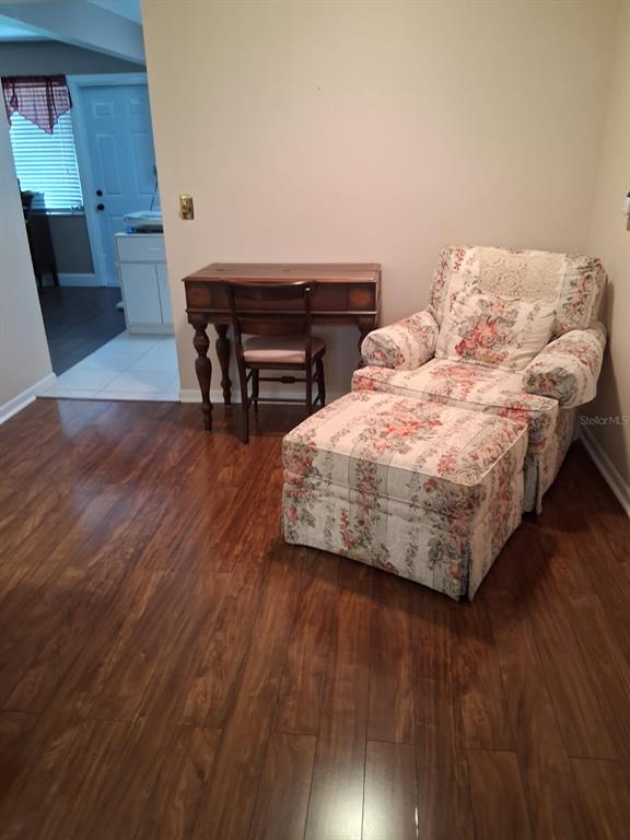 A floral armchair with an ottoman sits next to a wooden desk on hardwood floors — 6770 RIVIERA N, PINELLAS PARK, FL