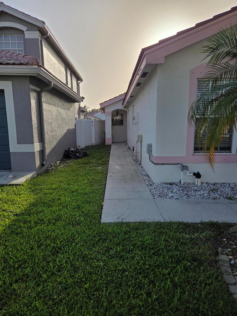 A concrete walkway leads between two houses toward a side entrance door — 7093 Middlebury Drive # 7093, Boynton Beach FL 33436, BOYNTON BEACH, FL
