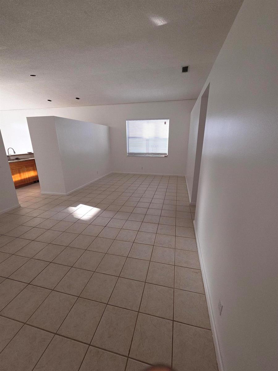 An empty room with beige tile flooring, white walls, and a partial partition wall — 7093 Middlebury Drive # 7093, Boynton Beach FL 33436, BOYNTON BEACH, FL