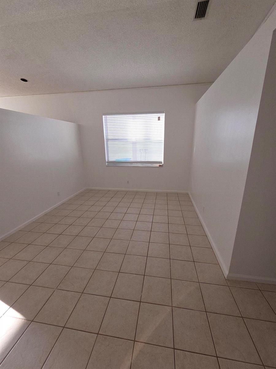 An empty room with white walls, beige tile flooring, and a single window with blinds — 7093 Middlebury Drive # 7093, Boynton Beach FL 33436, BOYNTON BEACH, FL