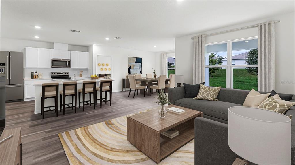 This open-concept living area features a kitchen with an island, dining space, and living room — 5175 NICKERBEAN STREET, APOPKA, FL
