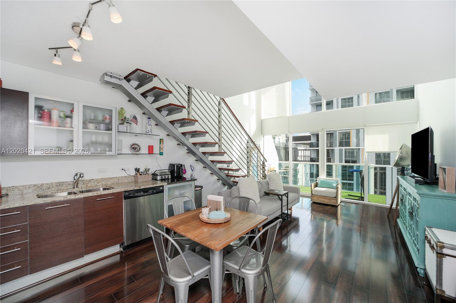 A modern open-concept living area features a kitchen, dining space, and staircase with metal railings — 41 SE 5th St # 704, Miami FL 33131, MIAMI, FL