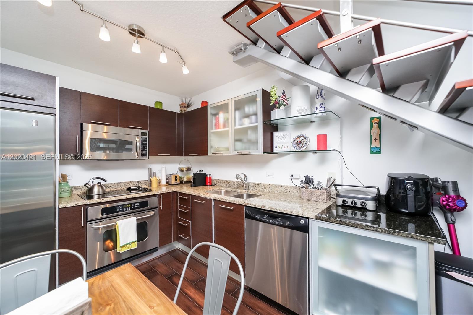 A modern kitchen features dark wood cabinets, stainless steel appliances, and an open staircase — 41 SE 5th St # 704, Miami FL 33131, MIAMI, FL