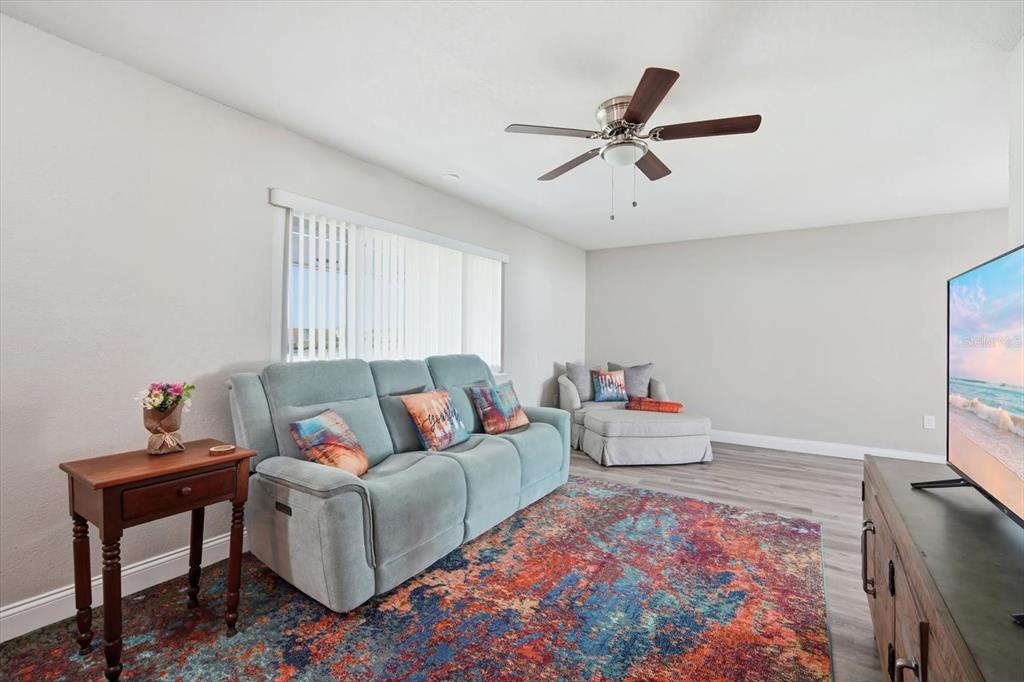 A living room features a blue sofa, a patterned rug, and a television on a stand — 1404 SETON HALL DRIVE, SUN CITY CENTER, FL