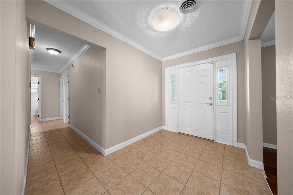 A tiled entryway features a white front door with sidelights and neutral-toned walls — 2009 SE 15TH LANE, OCALA, FL