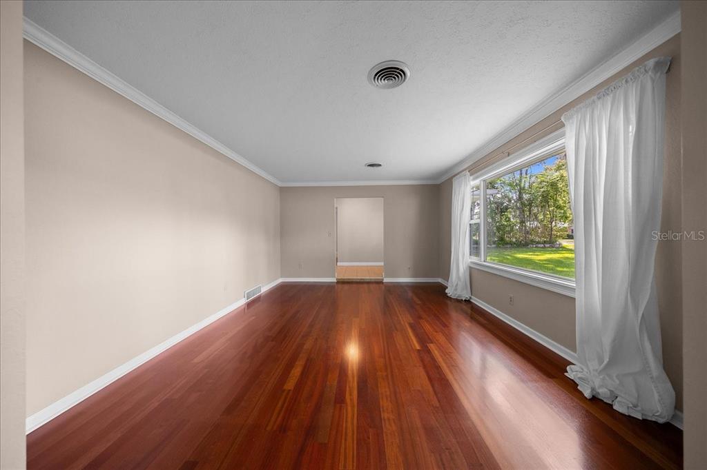 An empty room with hardwood floors, white walls, and a large window with curtains — 2009 SE 15TH LANE, OCALA, FL