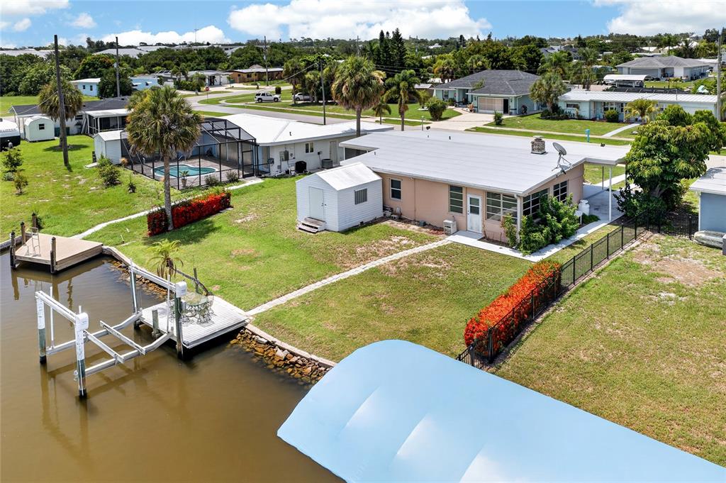 An aerial view shows a waterfront house with a dock, shed, and fenced yard — 321 WEBER TERRACE, PORT CHARLOTTE, FL