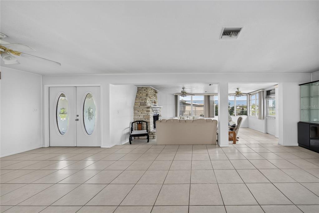 A spacious room with tiled floors, a stone fireplace, and double front entry doors — 321 WEBER TERRACE, PORT CHARLOTTE, FL