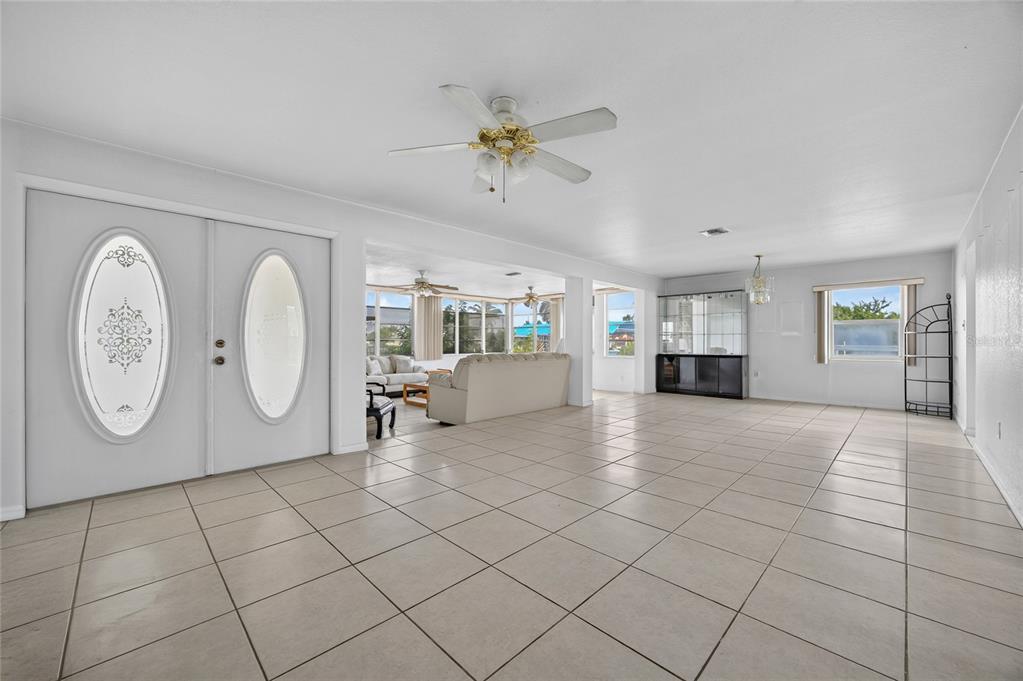 A spacious living area features white tile flooring, a ceiling fan, and double entry doors — 321 WEBER TERRACE, PORT CHARLOTTE, FL