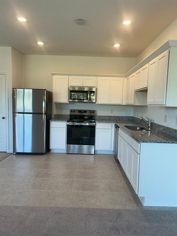An empty bedroom with beige carpet, white walls, and a window with horizontal blinds — 3270 VESARA DRIVE, DAVENPORT, FL
