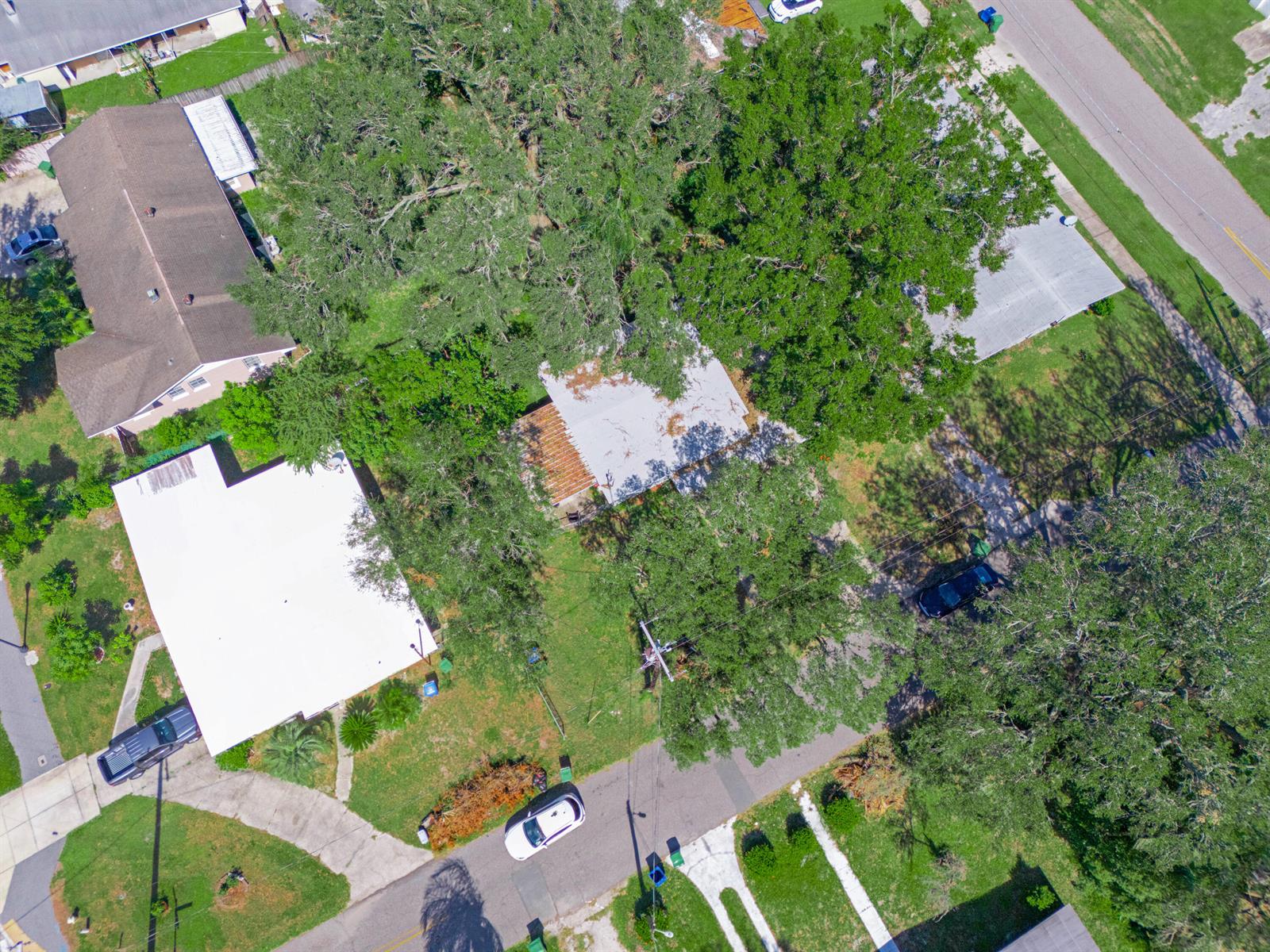An aerial view shows several houses with white roofs surrounded by large trees and driveways — 657 Ave C SW, Winter Haven FL 33880, WINTER HAVEN, FL