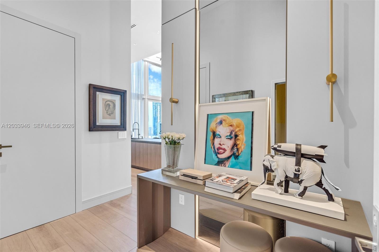 A modern entryway features a console table, decorative art, and a view into a kitchen — 475 Brickell Ave # 2215, Miami FL 33131, MIAMI, FL