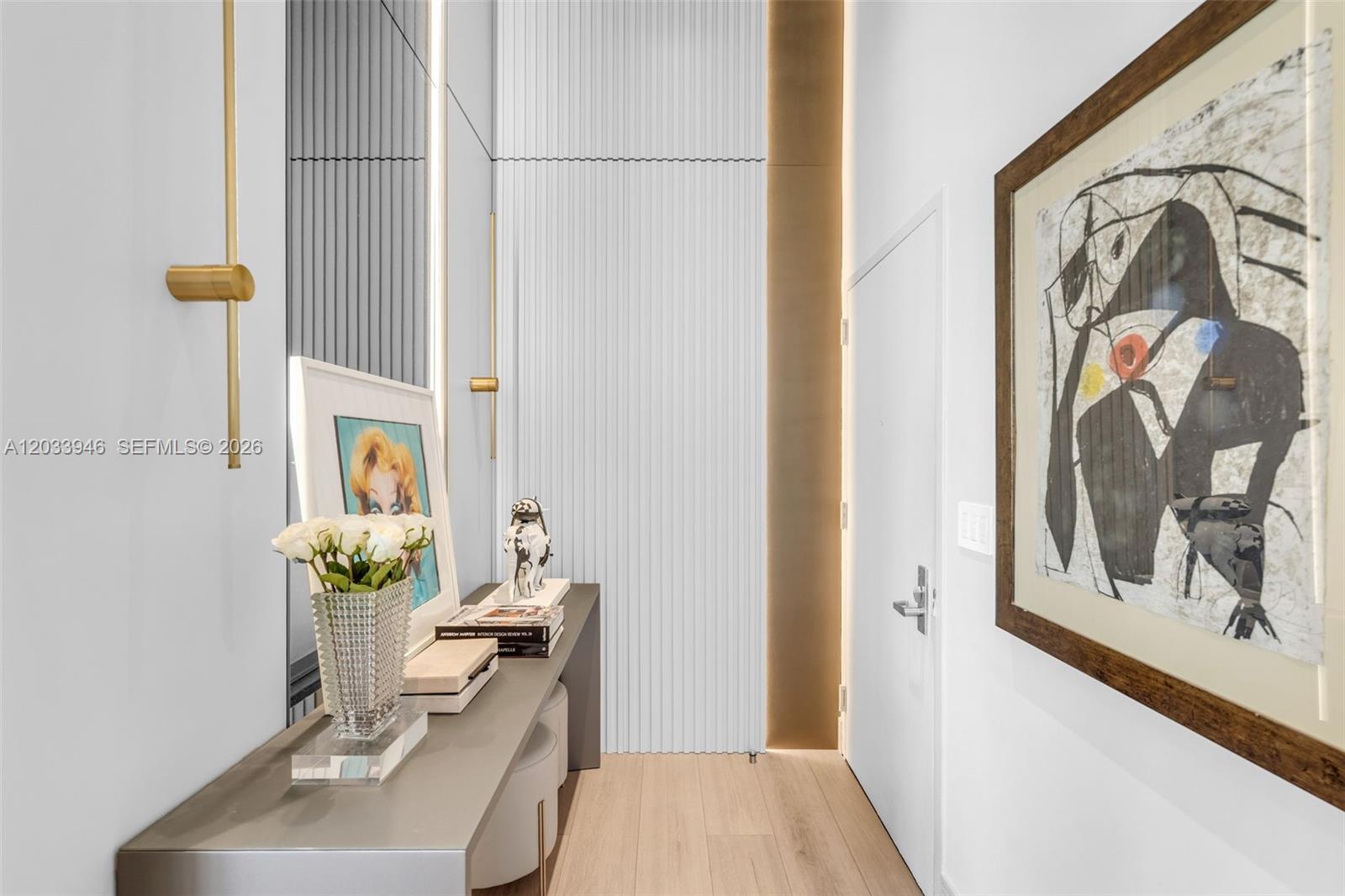 A modern hallway features light wood flooring, a console table, and abstract wall art — 475 Brickell Ave # 2215, Miami FL 33131, MIAMI, FL