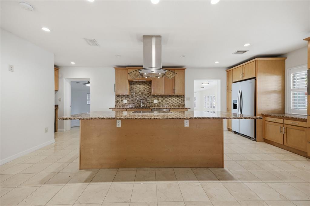 A kitchen features light wood cabinets, a granite island, stainless steel appliances, and tile flooring — 2512 W KANSAS AVENUE, TAMPA, FL