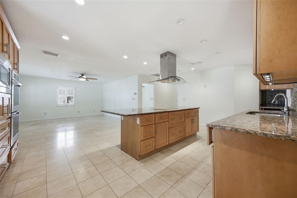 A kitchen with light wood cabinets, granite countertops, a central island, and tile flooring — 2512 W KANSAS AVENUE, TAMPA, FL