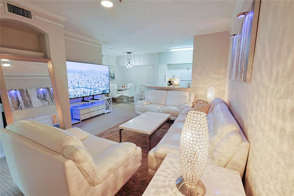 A living room features white leather sofas, a coffee table, and a large television — 4166 CENTRAL SARASOTA PARKWAY UNIT 512, SARASOTA, FL