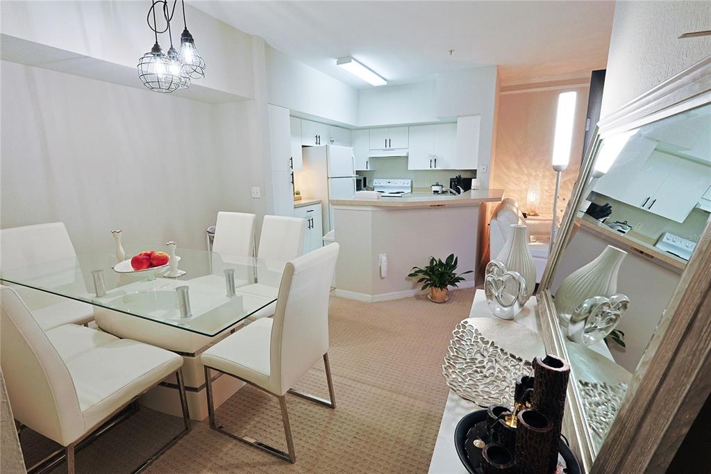 A dining area with a glass table and white chairs sits adjacent to a kitchen — 4166 CENTRAL SARASOTA PARKWAY UNIT 512, SARASOTA, FL