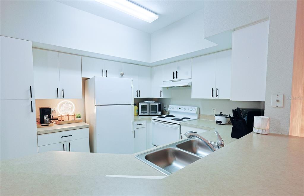 A kitchen features white cabinets, white appliances, and a double sink with laminate countertops — 4166 CENTRAL SARASOTA PARKWAY UNIT 512, SARASOTA, FL