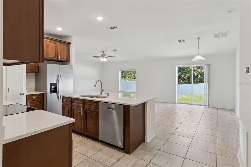 A kitchen with dark wood cabinets, stainless steel appliances, and a white quartz island — 2505 BAKER AVENUE E, HAINES CITY, FL