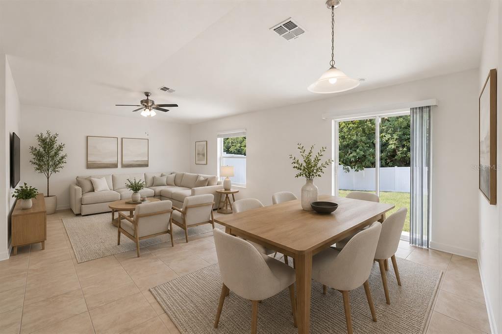 An open-concept living and dining area with light tile flooring and a sliding glass door — 2505 BAKER AVENUE E, HAINES CITY, FL