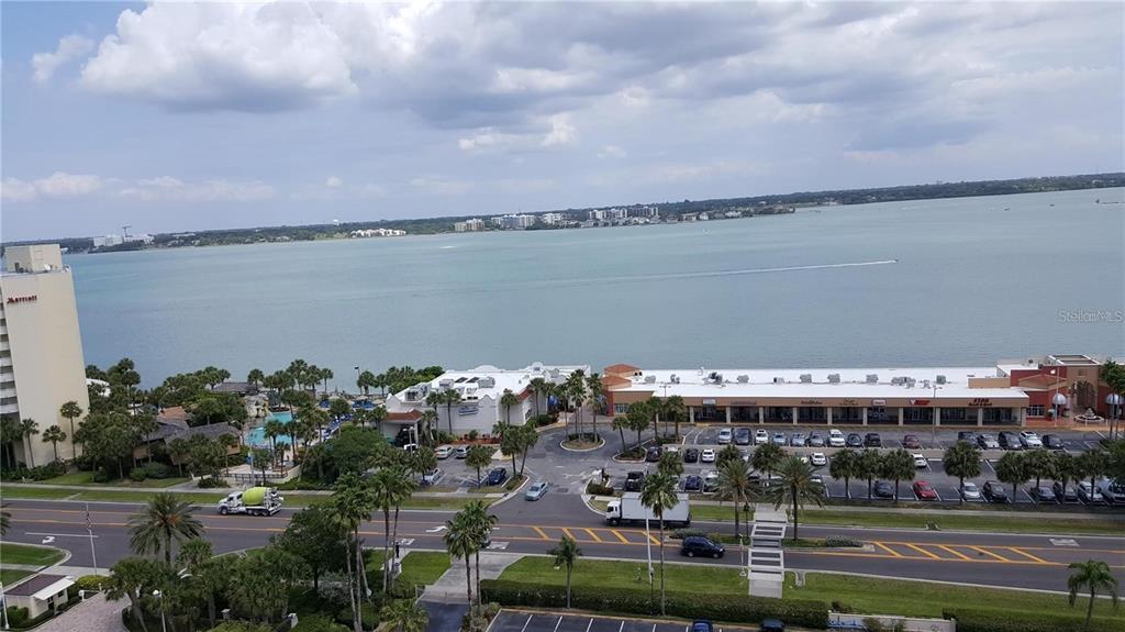 An elevated view shows a waterfront shopping center, a parking lot, and a nearby hotel — 1230 GULF BOULEVARD UNIT 1601, CLEARWATER BEACH, FL