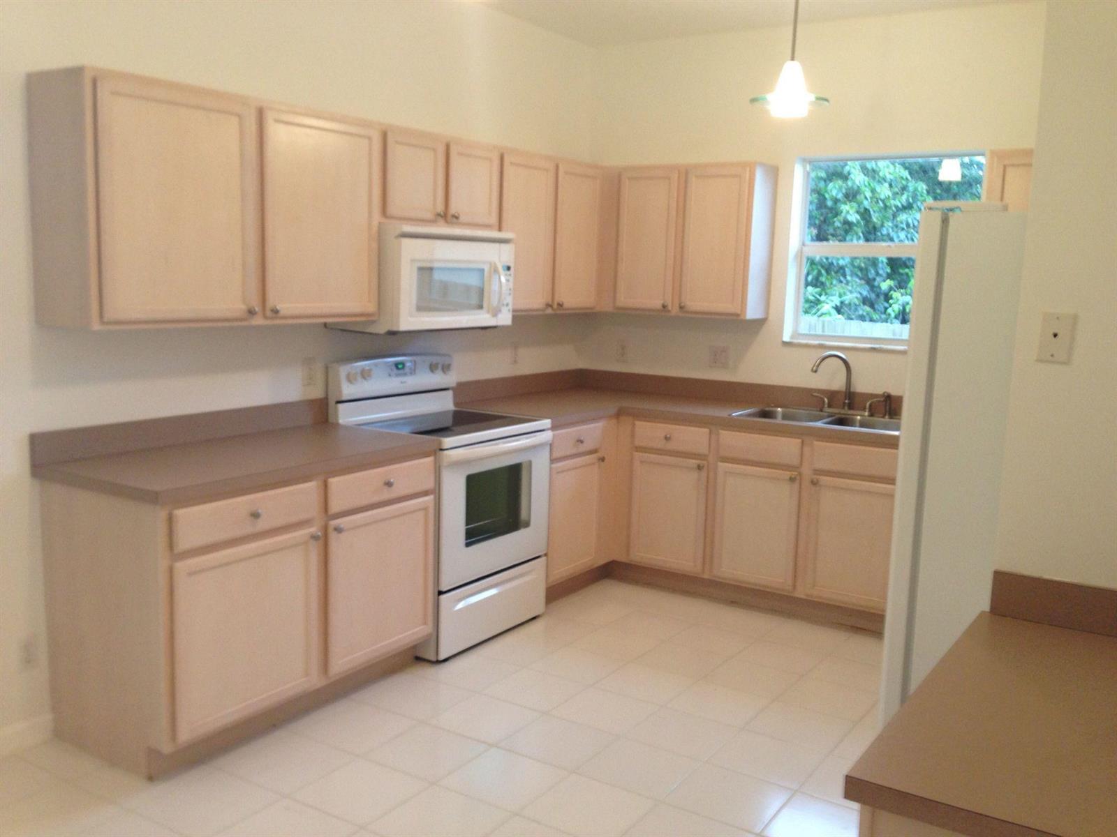 A kitchen with light wood cabinets, white appliances, tan countertops, and a window above the sink — 1731 Lavue Avenue, FL 33460, FL