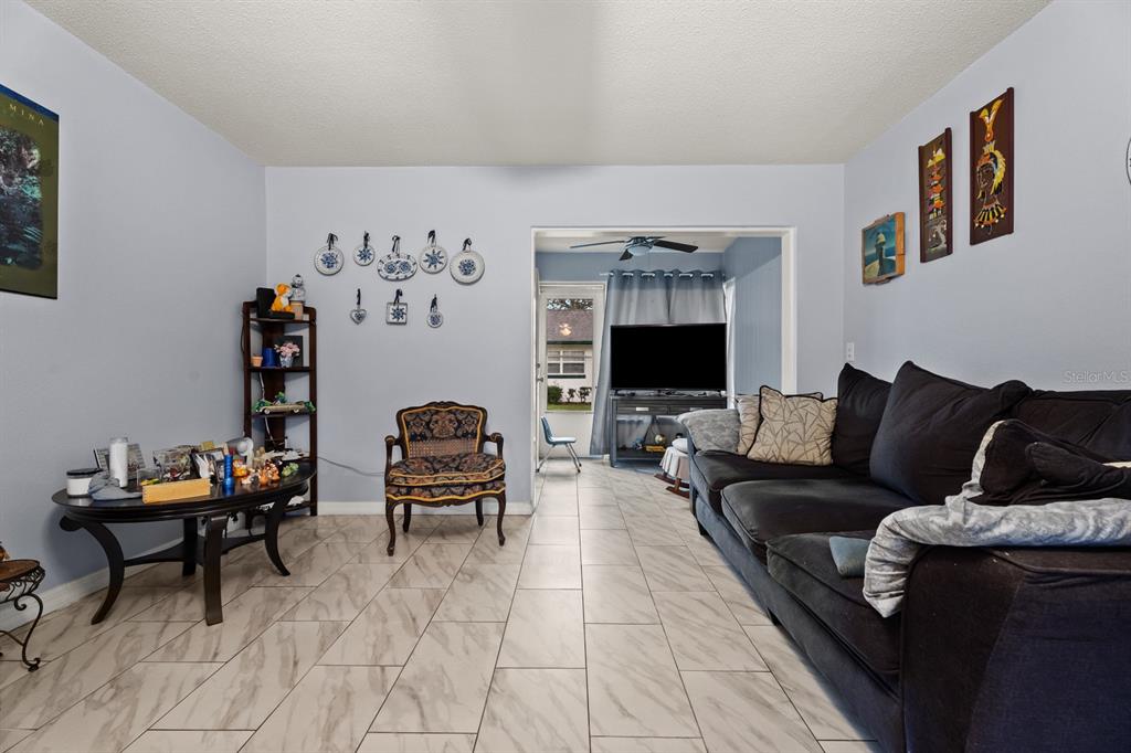 A living room features light-colored tile flooring, a dark sofa, and a wall of plates — 241 N HILL AVENUE, DELAND, FL
