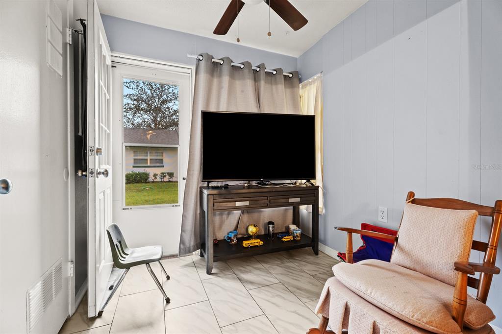 A sunroom with tile flooring, a television on a console, and a rocking chair — 241 N HILL AVENUE, DELAND, FL