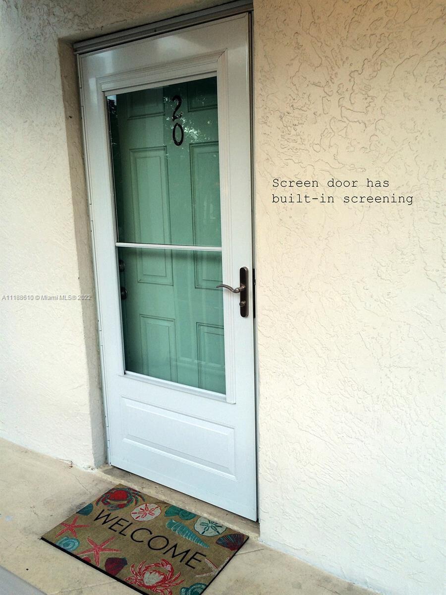 A white storm door with a screen panel stands at the entrance of a building — 300 Ocean Drive # 20, Key Largo FL 33037, KEY LARGO, FL