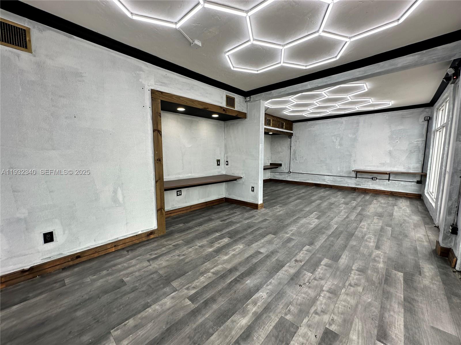 An office space features grey wood-look flooring, textured white walls, and geometric LED ceiling lights — 111 S 21 Ave, Hollywood FL 33020, HOLLYWOOD, FL
