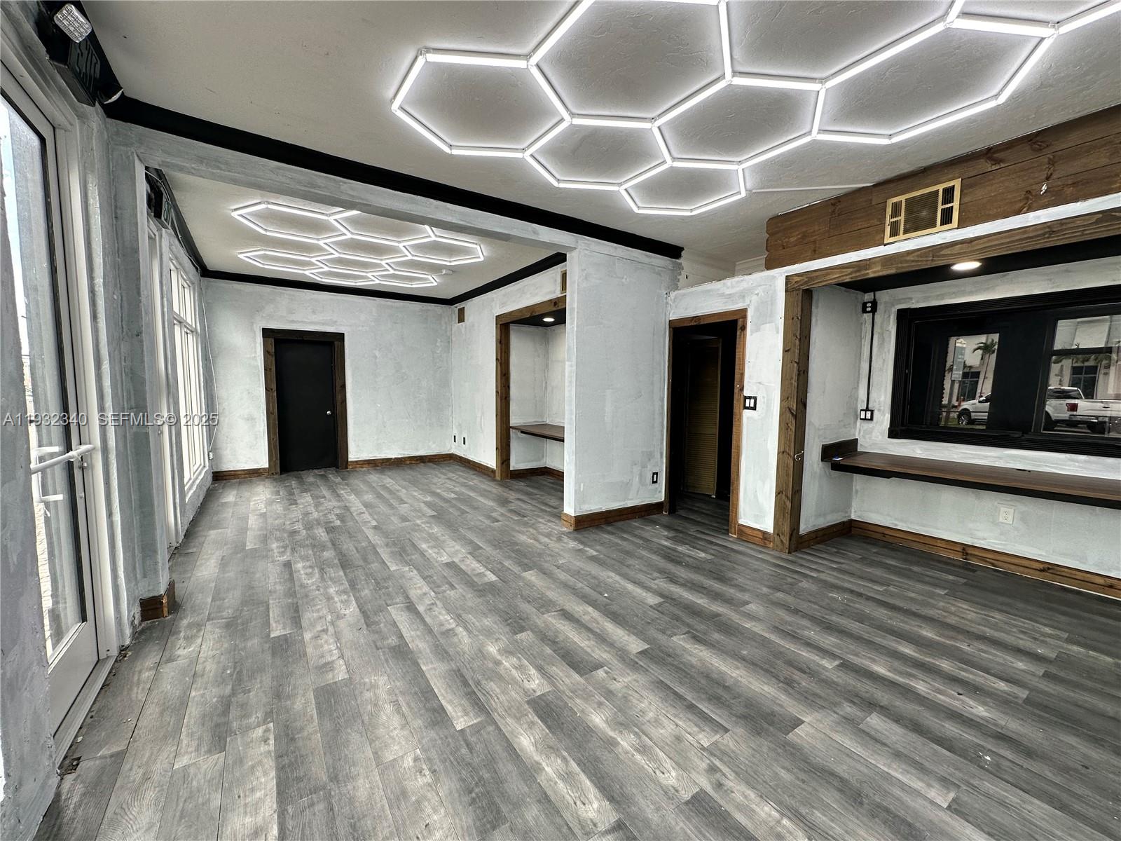 An interior room features gray wood-look flooring, white textured walls, and hexagonal LED ceiling lights — 111 S 21 Ave, Hollywood FL 33020, HOLLYWOOD, FL