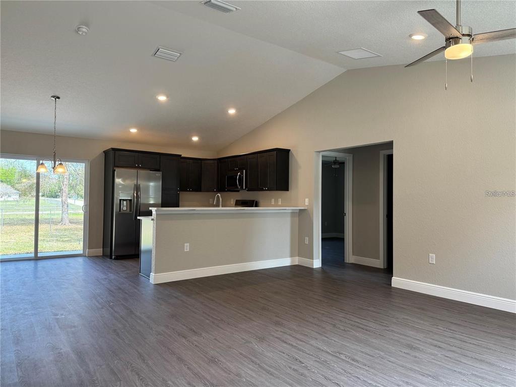 An open-concept kitchen with dark cabinets and a breakfast bar overlooks a living area — 3957 SE 137TH LANE, SUMMERFIELD, FL